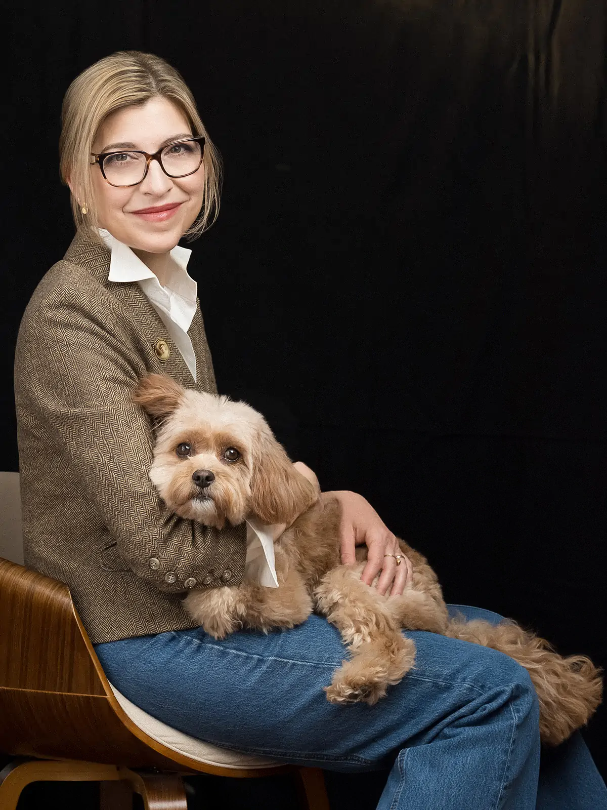 Photo of Julie Orringer in a blazer holding a dog against a dark background.